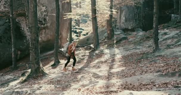 Странница в шляпе и рюкзаке бегает по лесу, смотрит вокруг крупным планом 4k — стоковое видео