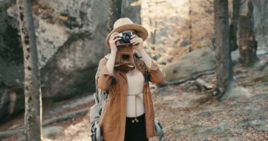 Kayalar bir orman üzerinde bir vintage film kamerası ile fotoğraf çekmek aktif sağlıklı beyaz bir kadın