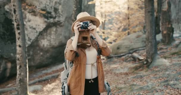 Wanita Kaukasia yang aktif dan sehat mengambil gambar dengan kamera film vintage di atas batu hutan — Stok Video