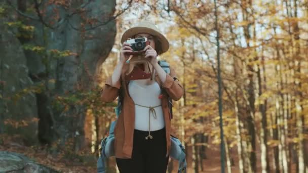 Retrato de una hermosa joven con sombrero tomando fotos en la vieja cámara vintage y sonriendo — Vídeo de stock