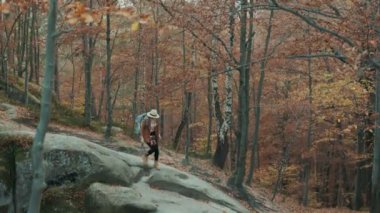 Boynunda, bir kamera ile şapkalı güzel dolaşıp kız seyahat sonbahar orman kayalara geçmiş üzerinden