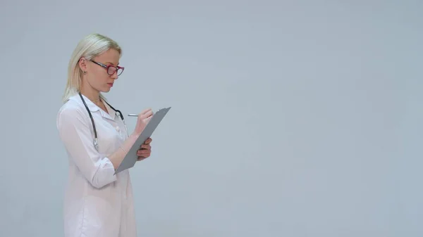 Lekarka w biały szlafrok i stetoskop uśmiech, rejestruje instrumentów — Zdjęcie stockowe
