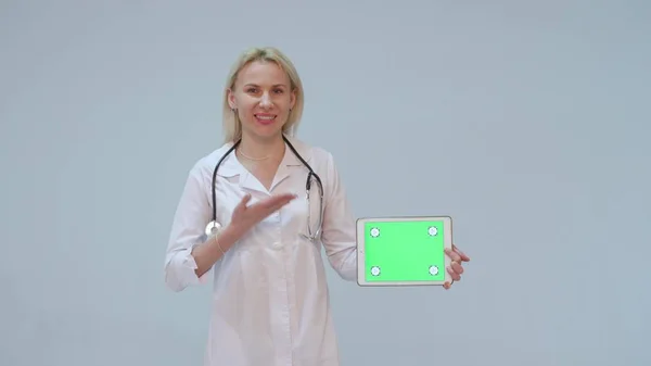Портрет женщины-врача в белом халате и планшете с зеленым экраном и стетоскопом улыбающейся — стоковое фото