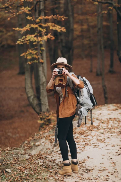 Femme caucasienne saine et active prenant des photos avec un appareil photo vintage sur un rocher forestier — Photo