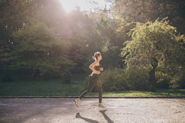 Güneşli sonbaharda açık egzersiz genç aktif kadın atlet. Park'a yakın çalışan.