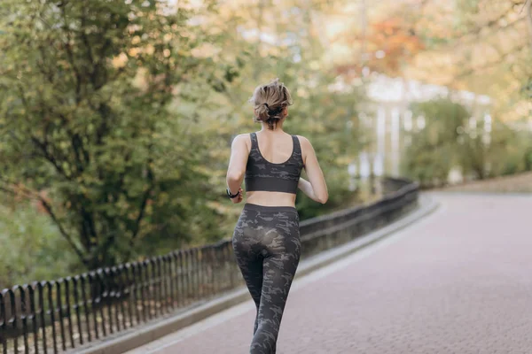 Runner woman running in park exercising outdoors fitness tracker