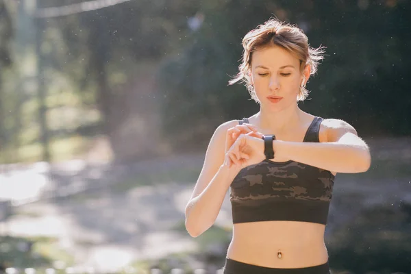 Femme de remise en forme dans les écouteurs sans fil en utilisant Smartwatch — Photo