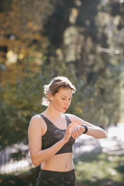 Mujer usando su smartwatch pantalla táctil dispositivo de tecnología portátil en las luces de la mañana — Foto de Stock