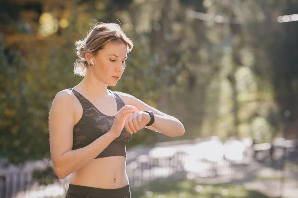 Femme utilisant son dispositif de technologie portable à écran tactile smartwatch dans les lumières du matin — Photo