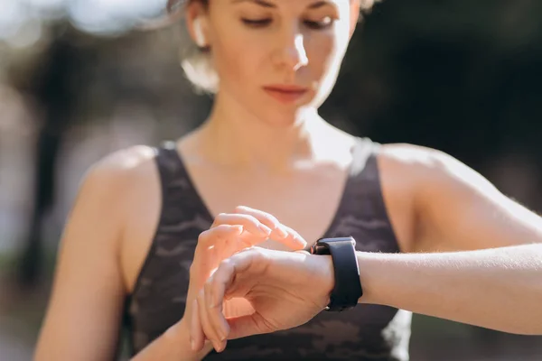 Mujer usando su smartwatch pantalla táctil dispositivo de tecnología portátil en las luces de la mañana — Foto de Stock