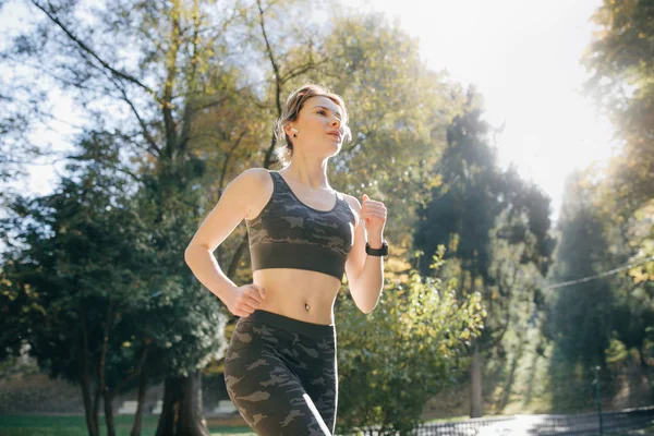 Çekici esmer kadın runner şehir park airpods bluetooth kulaklık kulaklık çalıştıran portresi. Sağlıklı fitness spor kadın açık havada koşu