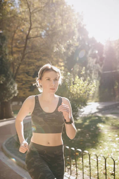 Fitness saludable atlética mujer corriendo al aire libre. Atractiva morena corredor femenino corriendo en el parque de la ciudad airpods bluetooth auriculares auriculares . — Foto de Stock