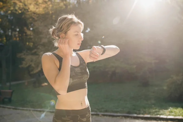 Corredor mujer comienza a correr en el uso de auriculares escuchando música — Foto de Stock