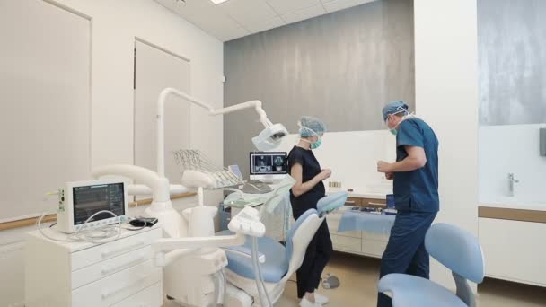 Dos dentistas discutiendo caso particular, tiro de interior en la oficina del dentista moderno — Vídeo de stock