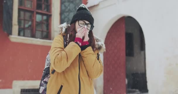 Kranke Frau mit Brille, die im Freien ihre Nase ins Gewebe bläst. junge Frau bekam Nasenallergie — Stockvideo
