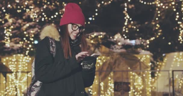 Attraktive und fröhliche junge Frau mit Smartphone in einer belebten Straße — Stockvideo