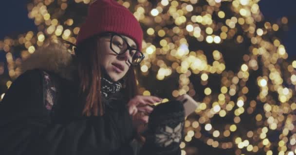 Attraktiv kvinna som använder mobiltelefon under promenaden på gatorna i Night Town — Stockvideo