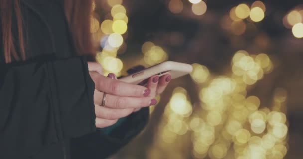 Primo piano di mani di donna con smartphone in città di notte. Tecnologia, inverno e vacanza concetto — Video Stock