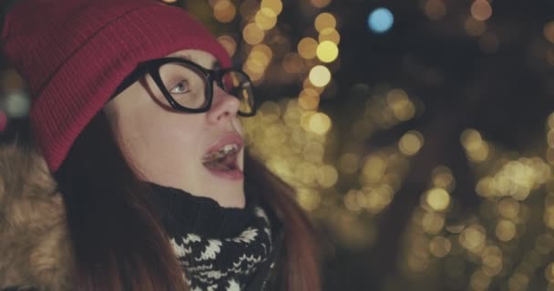 Närbild på den glad tjej söker Förhäxad på något på de suddiga julbelysning i natt — Stockvideo