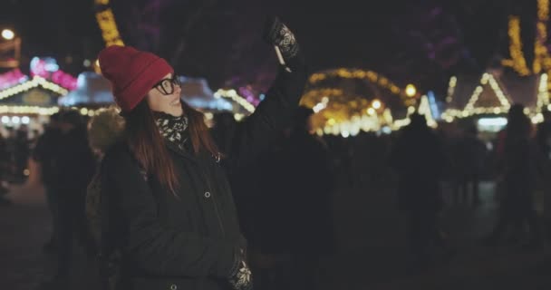Дівчина робить селфі за допомогою смартфона в зимовому місті вночі — стокове відео