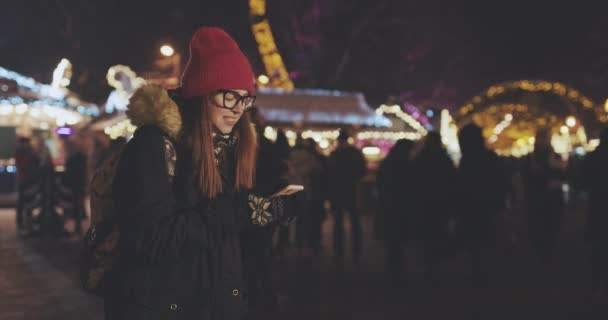 Женщины используют смартфон во время прогулки по городу ночью. в замедленной съемке — стоковое видео