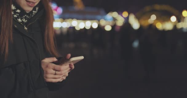 Mani di donna Utilizzando Smartphone al tramonto in città. Notte offuscata lampioni sfondo — Video Stock