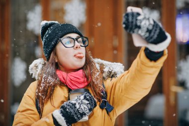 Çekici kız bardaklarda selfie onun smartphone üzerinde yapar. Kadın üstünde hareket eden telefon fotoğraf yapar. Her yerde olabilir.
