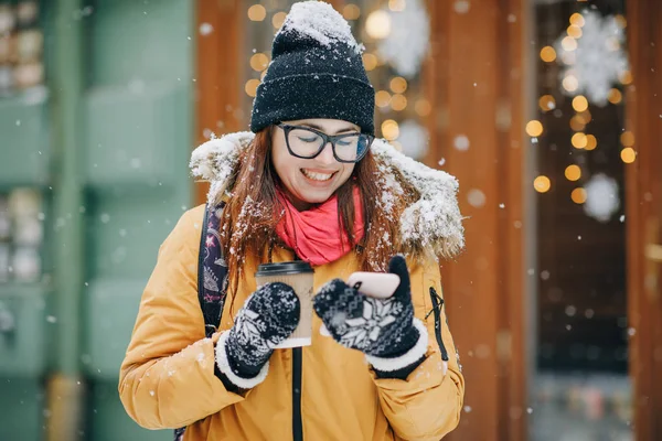 Aantrekkelijk en vrolijke jonge vrouw met behulp van smartphone in een straat. Ze is het controleren van mails, chats of het nieuws. Stad ten dage — Stockfoto