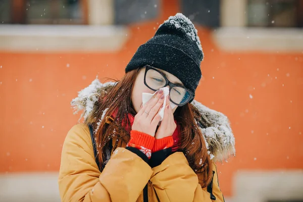 Młoda kobieta dmuchanie nosem w tkance w zimie — Zdjęcie stockowe