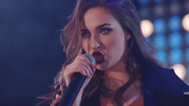 Mädchen singen mit Mikrofon, Sängerin mit Mikrofon, Musiksaal, gleißendes Licht im Hintergrund — Stockvideo