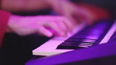 Erkek el oynamak piyano renkli sahne aydınlatma altında yakın çekim. Müzisyen bir takım gerçekleştirmek bir kompozisyon bir klavye müzik istasyonunda bir parti gecesi.