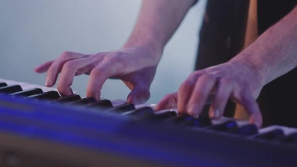 Close up mani uomo suonare il pianoforte elettrico sotto illuminazione scenica colorata — Video Stock