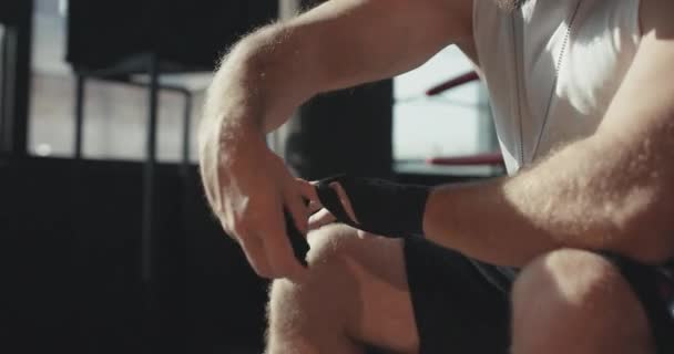 Boxeador masculino envuelve sus manos con un envoltorio negro antes del entrenamiento de lucha — Vídeo de stock