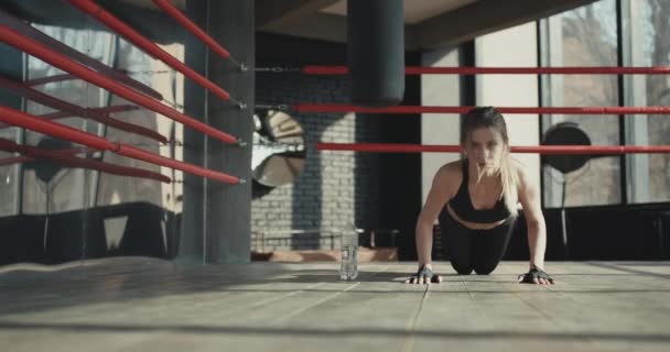 Фитнес-женщина делает отжимания на коврике для упражнений. Здоровая молодая женщина работает в студии — стоковое видео