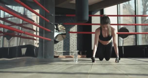 Güzel kadın itme yaparken kameraya bakarak ups--dan yavaş çekimde spor salonunda ahşap zemin — Stok video