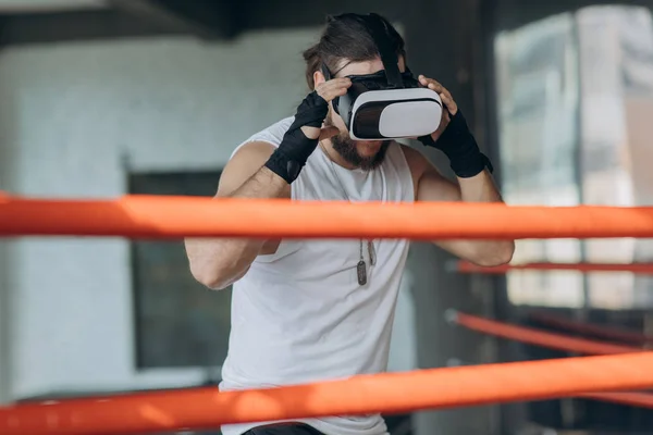Attractive man boxing in VR 360 headset training for kicking in virtual reality
