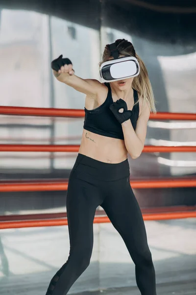 Woman boxing in VR 360 headset training for kicking in virtual reality