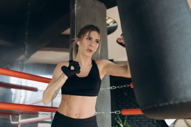 Erkek spor salonunda boks torbasına boks eldivenleri ile Delme