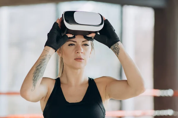 Attractive woman boxing in VR 360 headset training for kicking in virtual reality