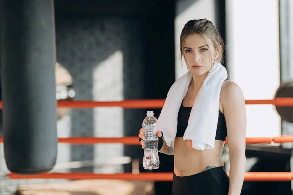 Mujer de fitness sedienta descansando tomando un descanso con la bebida botella de agua en el interior después del entrenamiento — Foto de Stock