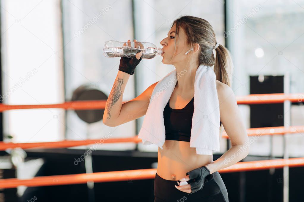 Closeup view of a young woman having a break after hard training by the boxing bag