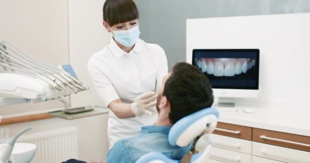 Dentists with a patient during a dental intervention to man — Stock Video