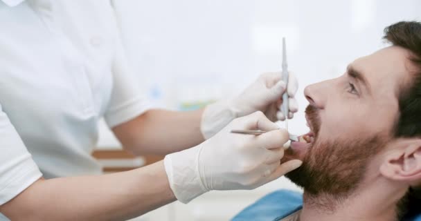 Молодой мужчина с открытым ртом во время осмотра у стоматолога — стоковое видео