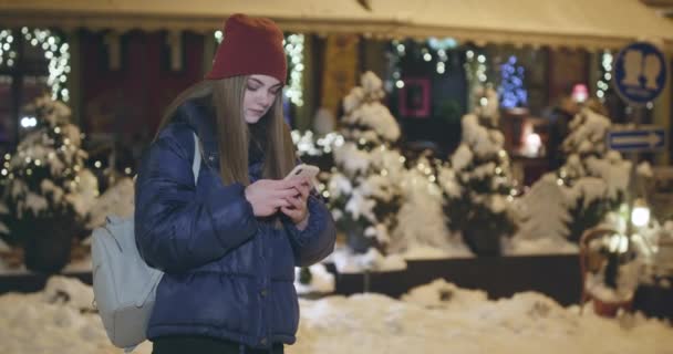 Uso del teléfono móvil durante el paseo por las calles de la ciudad nocturna — Vídeo de stock