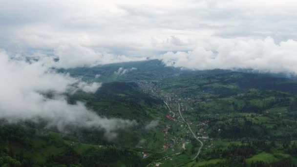 Vol dans les nuages. Une vue de la terre à travers les nuages. Une route de montagne sinueuse. La route est sur les hauteurs des collines forestières — Video