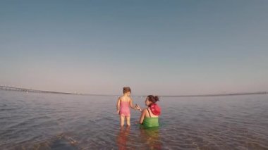 Anne küçük kızlarıyla birlikte kucaklaşmak ve denize koşmak için oynar. mutlu anne ve kız kavramı, mutluluk kavramı ve denizde cildi korumak için kremler, mutlu çocuklar