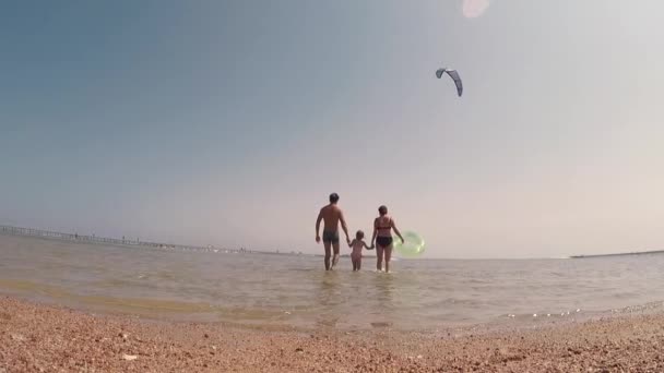 Szczęśliwa rodzina na plaży trzymając ręce swinging dziewczynka wokół o zachodzie słońca na wakacjach — Wideo stockowe