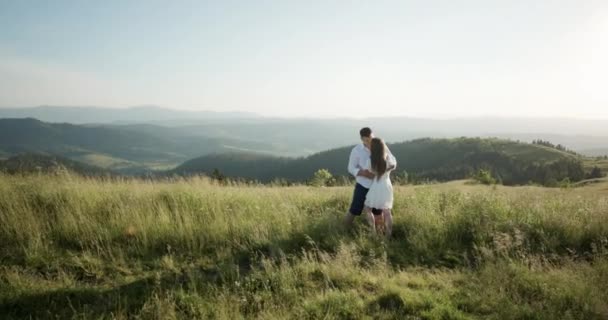 Молода чарівна пара обіймає, цілує один одного в зеленому щільному гірському регіоні. Літо, захід сонця. Пара цілей. Назавжди закоханий. Історія кохання — стокове відео