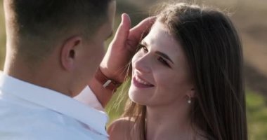 Yakın çekim sevimli çift kucaklayan, yeşil yoğun dağ bölgesinde birbirlerini öpüyor. Yaz, gün batımı. Birkaç gol. Aşk hikayesi