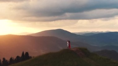 Sevgi dolu çift birbirlerine sarılıp öpüşüyorlar. Erkekler şefkat ve sevgi ile kız arkadaşı öpüyor. Dağ arka planı